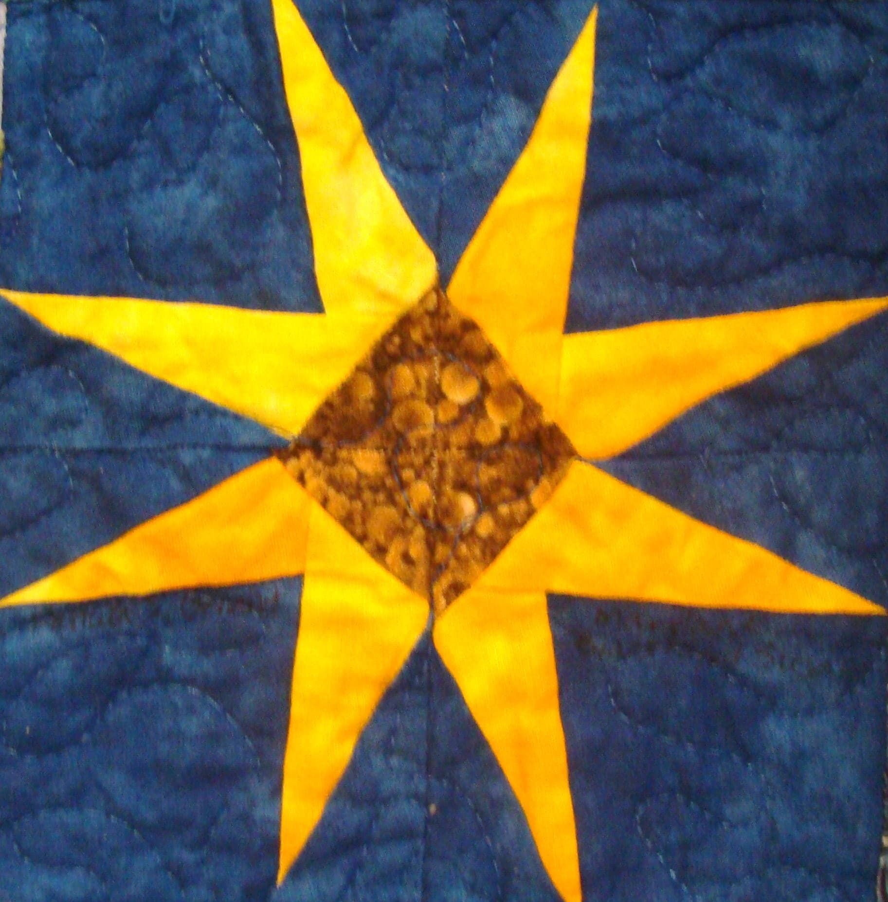 A black-eyed Susan star block in gold on blue from a NiftyFifty swap