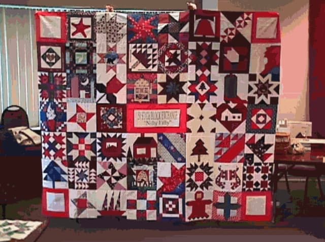 The NF 1 Breast Cancer Charity quilt held up by Nifty Fifty quilters after they had finishing piecing it together in 1998.